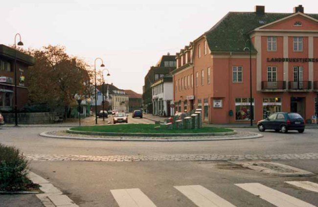 Fotografi av en rundkjøring. Rundt rundkjøringen er det steinlagt, og i rundkjøringen er det en skulptur