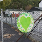 Foto av et grønt hjerte festet på et gjerde utenfor en skole.