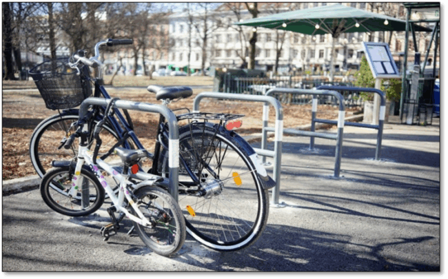 Foto som viser stativer kalt A-stativer. Disse og tilsvarende l&oslash;sninger gir god st&oslash;tte og l&aring;semuligheter, ettersom de passer sykler av forskjellige st&oslash;rrelser. Stativene er formet som en stor og bred &laquo;A&raquo;. P&aring; bildet er det fire A-stativer, hvor det er l&aring;st en voksensykkel og en barnesykkel til samme stativ, som illustrerer at stativtypen passer til flere sykkelst&oslash;rrelser.