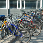 sykler parkert ved et langt sykkelstativ utenfor et bygg