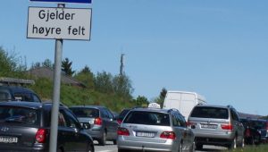 Bilde av biler som står i kø ved et skilt som sier 2+ foran bildet av en bil og kommuniserer at dette gjelder for høyre felt.