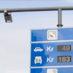 Foto av et skilt som viser veiprisene (bompengetakstene) for personbiler og tunge kjøretøy.