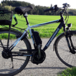 Elsykkel med kurv parkert på landevei.