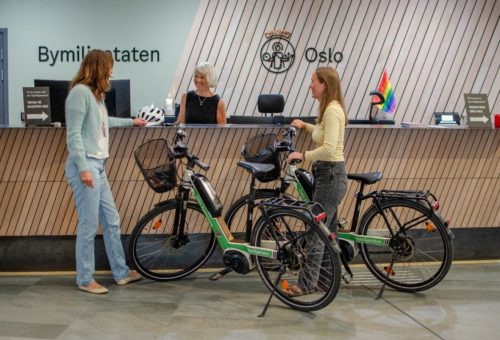 Bildet viser to ansatte som henter ut bedriftssykler fra en resepsjon.