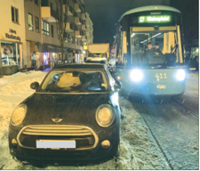 Fotoet viser en bil som står parkert i veien for trikken.