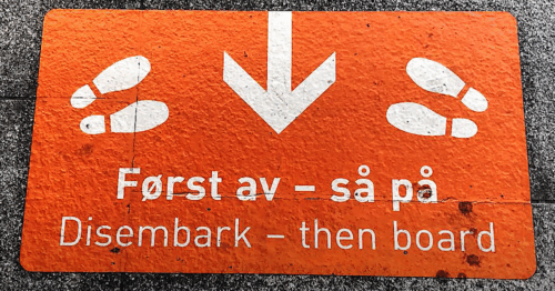 Foto av et skilt som oppfordrer folk til å slippe av passasjerer som skal av, før de selg går om bord.