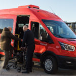 Fotoet viser en minibuss fra Ruter, der en eldre mann hjelpes ombord i bussen.