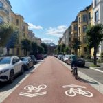 Fotoet viser en sykkelprioitert gate i Oslo. En syklist sykler på en sykkelvei i en typisk bygate.