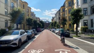 Fotoet viser en sykkelprioitert gate i Oslo. En syklist sykler på en sykkelvei i en typisk bygate.