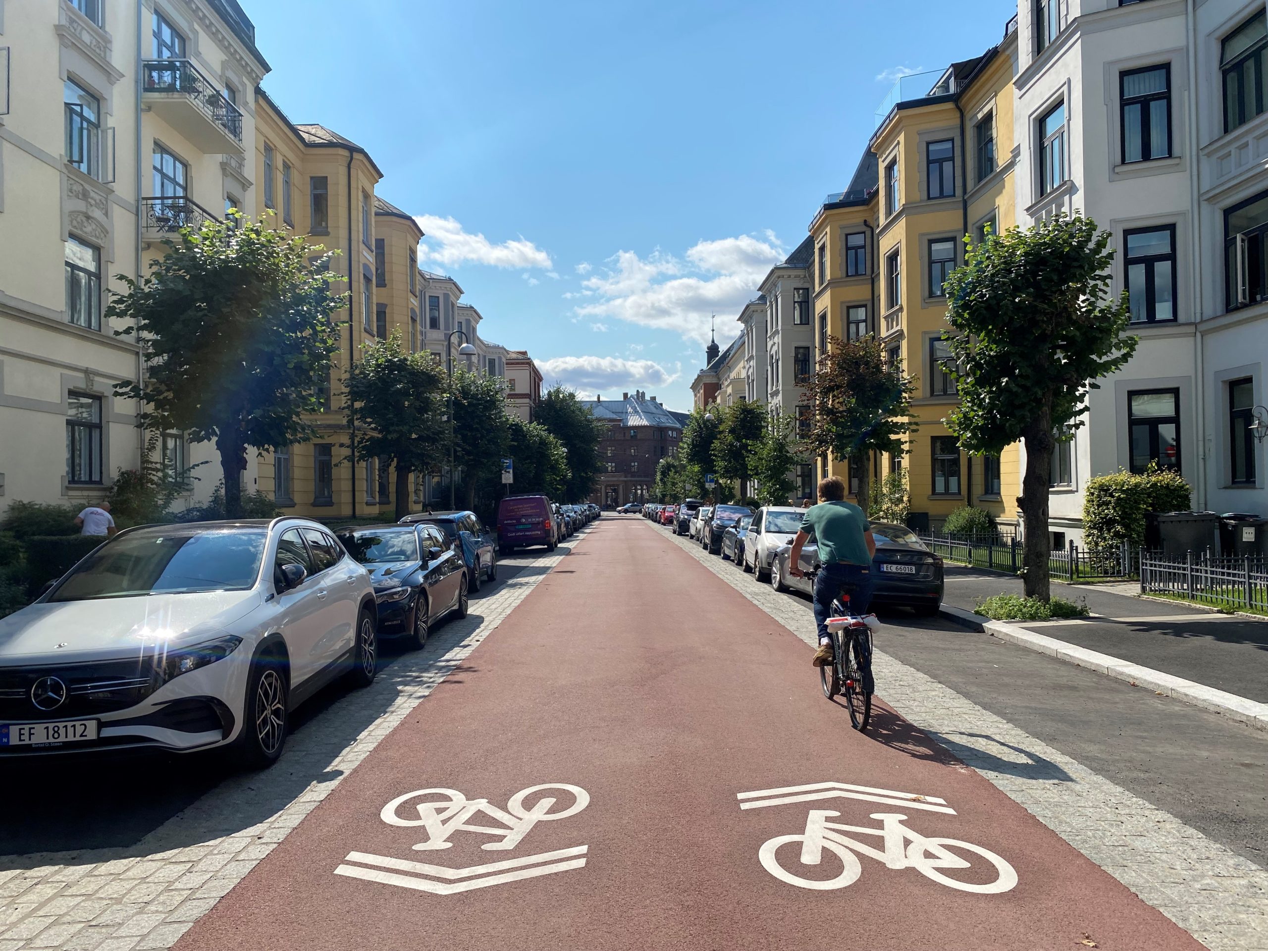 Fotoet viser en sykkelprioitert gate i Oslo. En syklist sykler p&aring; en sykkelvei i en typisk bygate.
